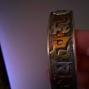 It is a bronze silver bangle type bracelet with unique symbols on it